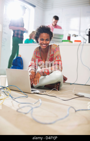 Imprenditrice utilizzando laptop sul pavimento Foto Stock