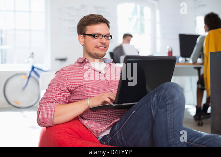 Uomo d affari con computer portatile in poltrona sacco in office Foto Stock