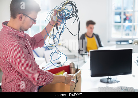 Imprenditore untangling cordicelle in ufficio Foto Stock
