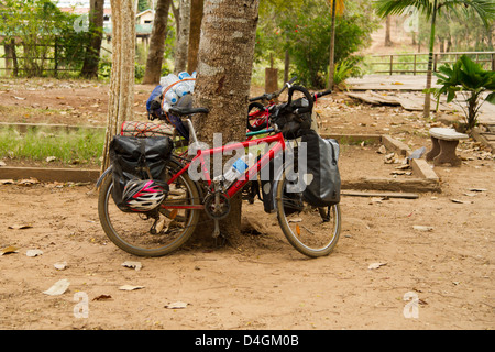 Un molto carico touring bike si appoggia contro un albero Foto Stock