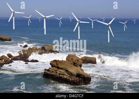 Diversi impianti eolici offshore sulla linea di orizzonte su sfondo con cielo nuvoloso Foto Stock