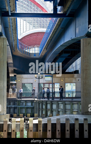 Ufficio i lavoratori e gli imprenditori al di sotto della Docklands Light Rail Bridge e alla stazione di Canary Wharf a Londra, Inghilterra Foto Stock