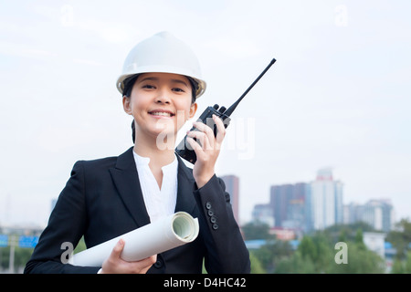 Giovani donne architetto con intercom e blueprint all'aperto Foto Stock