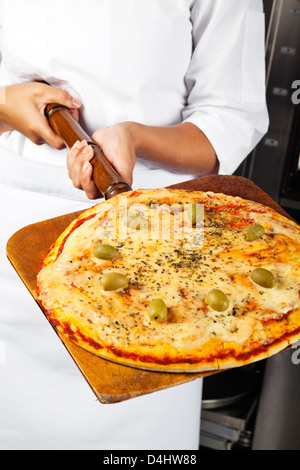 Lo Chef femmina tenendo la Pizza sulla pala Foto Stock