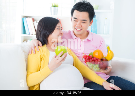 Donna incinta mangiare frutta a casa. Gravidanza giovane healthcare concetto. Foto Stock