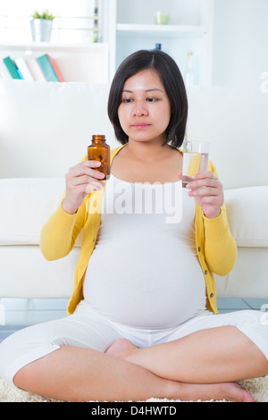 Donna incinta prendendo supplementi a casa. Foto Stock