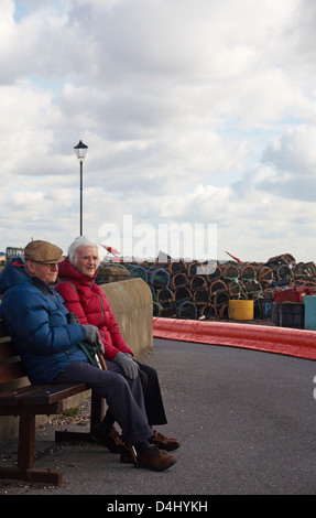 Vecchia coppia sat sul banco a Mudeford Quay nel Marzo Foto Stock