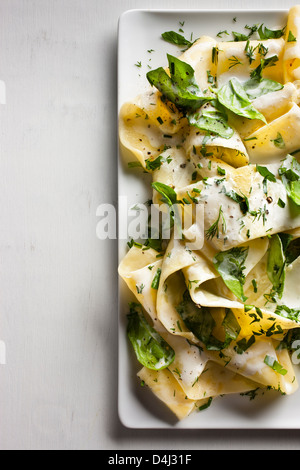 Un piatto di pappardelle con crema di ricotta, baby spinaci erbe fresche e pepe nero. Foto Stock