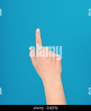 Effettuare a mano un gesto di sfioramento o touchscreen o un dispositivo di puntamento con un dito di una mano isolata contro uno sfondo blu Foto Stock