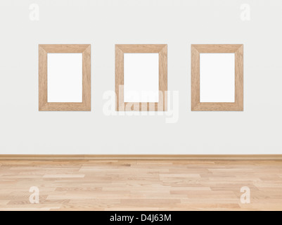 Tre rettangolare vuoto cornici in legno visualizzati su un muro bianco al di sopra di un legno duro con pavimento in legno. Foto Stock