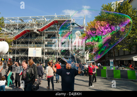 Un uomo facendo grandi bolle di sapone di fronte al Centre Pompidou di Parigi Foto Stock