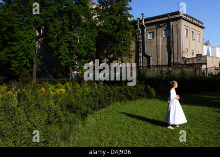 Ragazza la prima comunione vestito in il giardino nel cortile di una vecchia chiesa di Lodz, Polonia Foto Stock