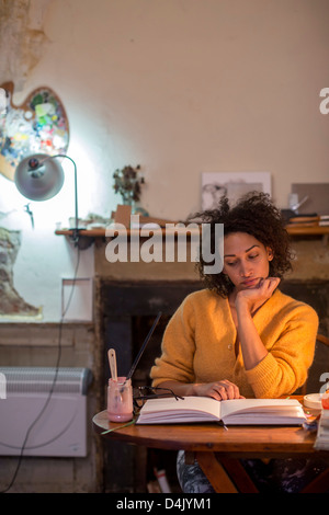 Donna libro di lettura alla scrivania Foto Stock