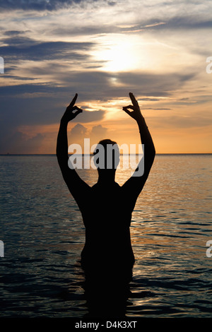 Silhouette di uomo meditando in acqua Foto Stock