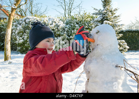 Ragazzo rendendo pupazzo di neve in giardino Foto Stock
