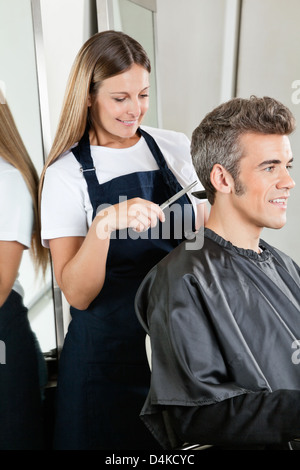 Parrucchiere dando scarti da client a Salon Foto Stock