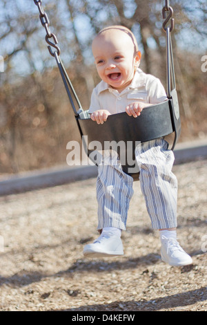 Baby boy giocando su swing in posizione di parcheggio Foto Stock