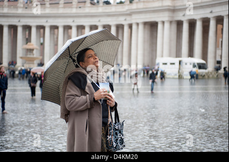 Donna con ombrello prega in piazza san pietro Foto Stock