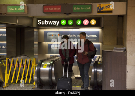 Due persone uscire dalla metropolitana escalator in Grand Central Station in New York City Foto Stock