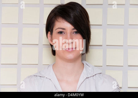 Giovane donna accanto alla parete di carta adesiva note. Foto Stock