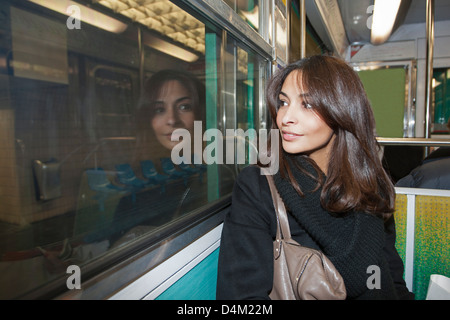 Donna sorridente in sella alla metropolitana Foto Stock