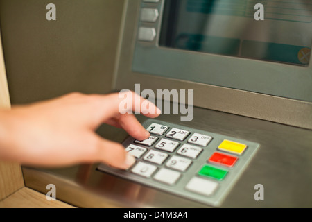 Donna utilizzando il tastierino su ATM Foto Stock