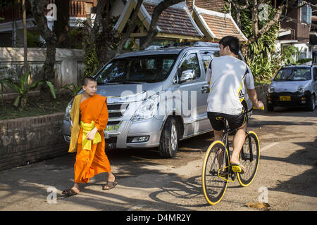 Marzo 11, 2013 - Luang Prabang, Luang Prabang, Laos - un debuttante buddista andando a Wat Xieng Thong, il più antico tempio buddista in Luang Prabang, parla di un ciclista pedalando attraverso il tempio. (Credito Immagine: © Jack Kurtz/ZUMAPRESS.com) Foto Stock