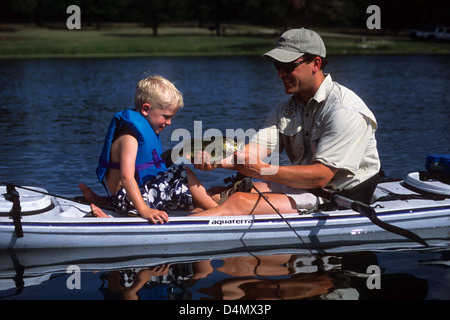 Padre e figlio di prendere un largemouth bass (micropterus salmoides) su un piccolo laghetto nei pressi di Austin in Texas Foto Stock