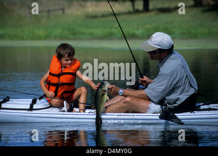 Padre e figlio di prendere un largemouth bass (micropterus salmoides) su un piccolo laghetto nei pressi di Austin in Texas Foto Stock