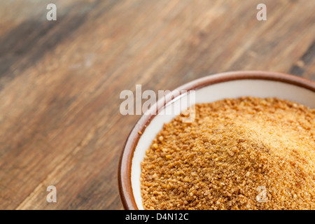 Piccolo vaso in ceramica degli oli di noce di cocco zucchero palm contro un fuori fuoco sfondo legno - Spazio di copia Foto Stock