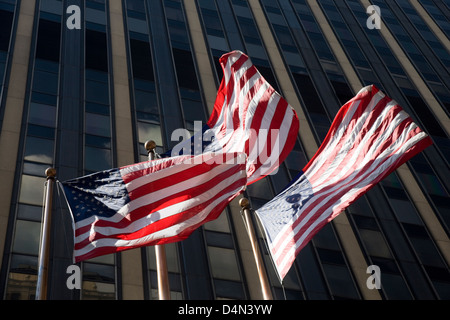 Tre di noi a stelle e strisce bandiere che sventolano al vento nella parte anteriore di un grattacielo di New York, Stati Uniti d'America Foto Stock