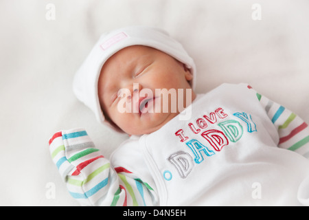 Sleeping Baby girl (8 giorni) prese in un soffice luce (luce tenda). Hat legge "carino" e top legge 'I love Daddy'. Foto Stock