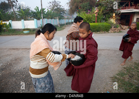 I monaci buddisti di riso di ricezione da un villaggio donna rurale in Birmania Foto Stock