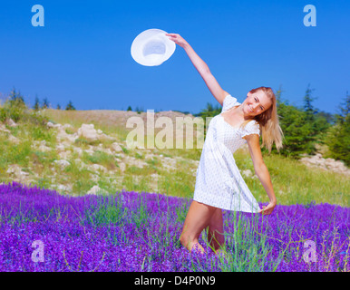 Ragazza carina che danzano sul campo di lavanda, bella donna felice godendo viola floral glade, piuttosto allegro giovane donna a piedi Foto Stock