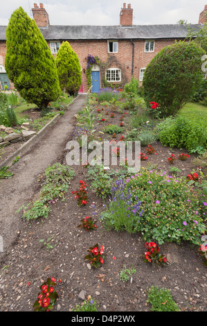 Vittoriano tradizionale inglese a terrazze giardino cottage stabiliti con biancheria da letto piante accanto a un lungo percorso dritto alla porta anteriore Foto Stock