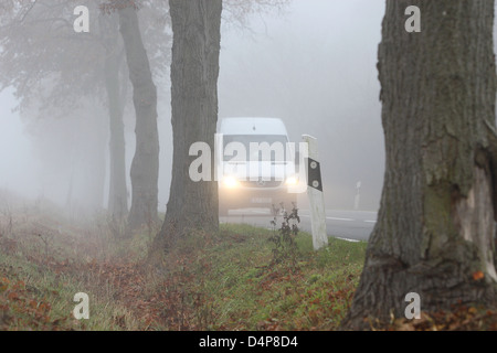 Blankenfelde, la Germania, il traffico automobilistico sulla strada di un paese nella nebbia Foto Stock