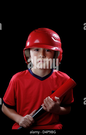Giovane ragazzo serio con il baseball rosso casco su sfondo nero - drammatico lo stile di illuminazione Foto Stock