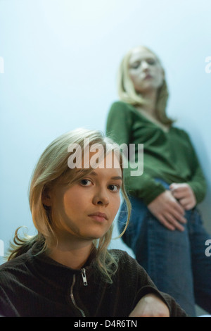 Ragazza adolescente guardando la telecamera, amico in background Foto Stock