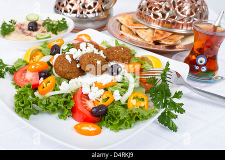Falafel insalata con pane pita e Hummus piastra, complementate con tè su un tavolo bianco panno. Foto Stock
