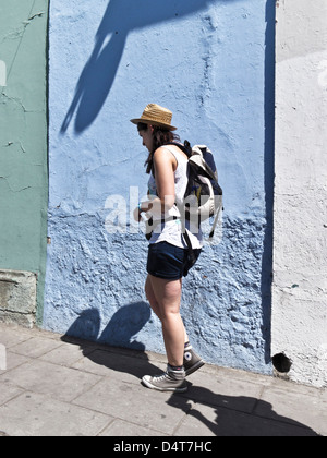 Piuttosto giovane turista nello zaino cappello di paglia e alte cime passeggiate lungo il marciapiede sulla bella e soleggiata giornata di primavera in Messico Oaxaca Foto Stock