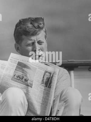 Restaurata digitalmente vintage foto del Presidente John F. Kennedy rilassante al di fuori, di fumare un sigaro e leggendo il giornale. Foto Stock