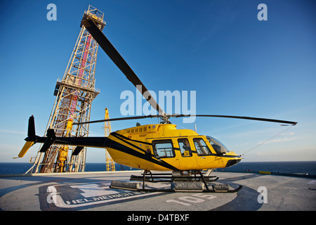 Una campana 407 elicottero utility su elisuperficie di un impianto di trivellazione petrolifera. Foto Stock