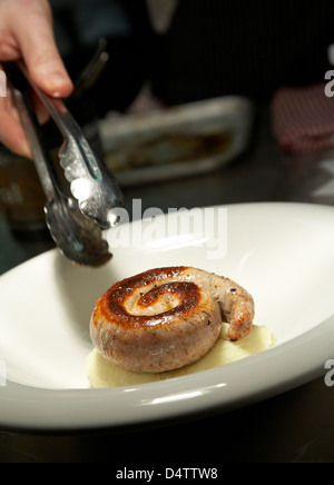 Lo Chef collocando un salsicce Cumberland su un letto di purea di patate in un ristorante nel Regno Unito. Foto Stock