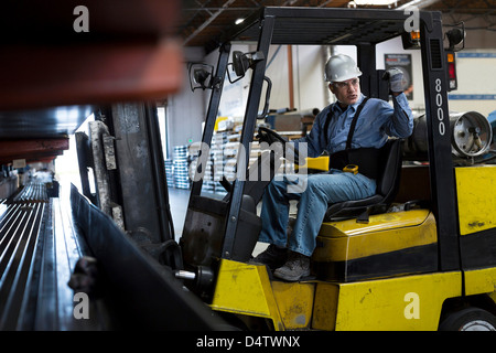 Lavoratore utilizzando un carrello elevatore in pianta in metallo Foto Stock