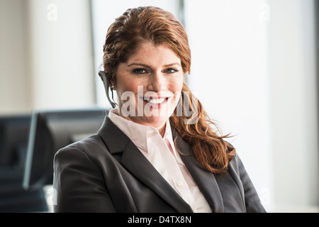 Sorridente imprenditrice di indossare le cuffie Foto Stock