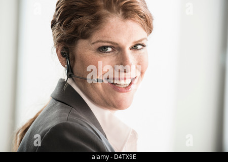 Sorridente imprenditrice di indossare le cuffie Foto Stock