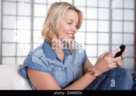 Donna che utilizza il telefono cellulare sul divano Foto Stock