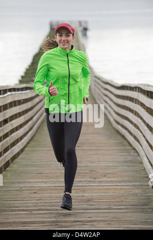 La donna in esecuzione sul dock in legno Foto Stock