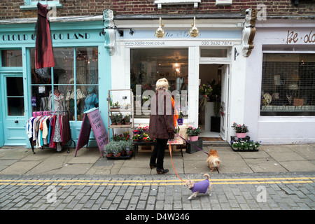 Donna che guarda le piante al di fuori del negozio a piedi il suo piccolo cani su Charlton posto vicino al passaggio di Camden Islington nel nord di Londra Inghilterra REGNO UNITO KATHY DEWITT Foto Stock