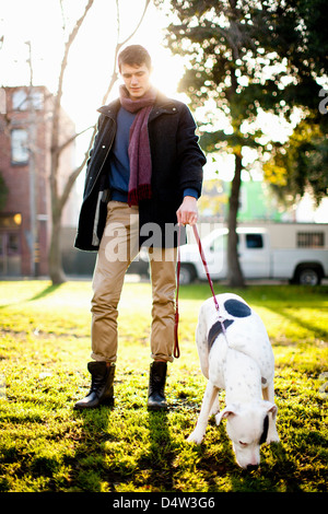 Uomo che cammina il cane in posizione di parcheggio Foto Stock